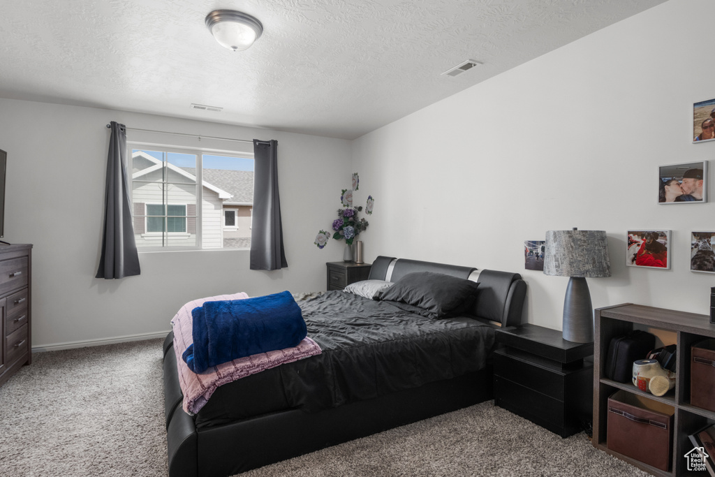 Bedroom with carpet, a textured ceiling, and baseboards