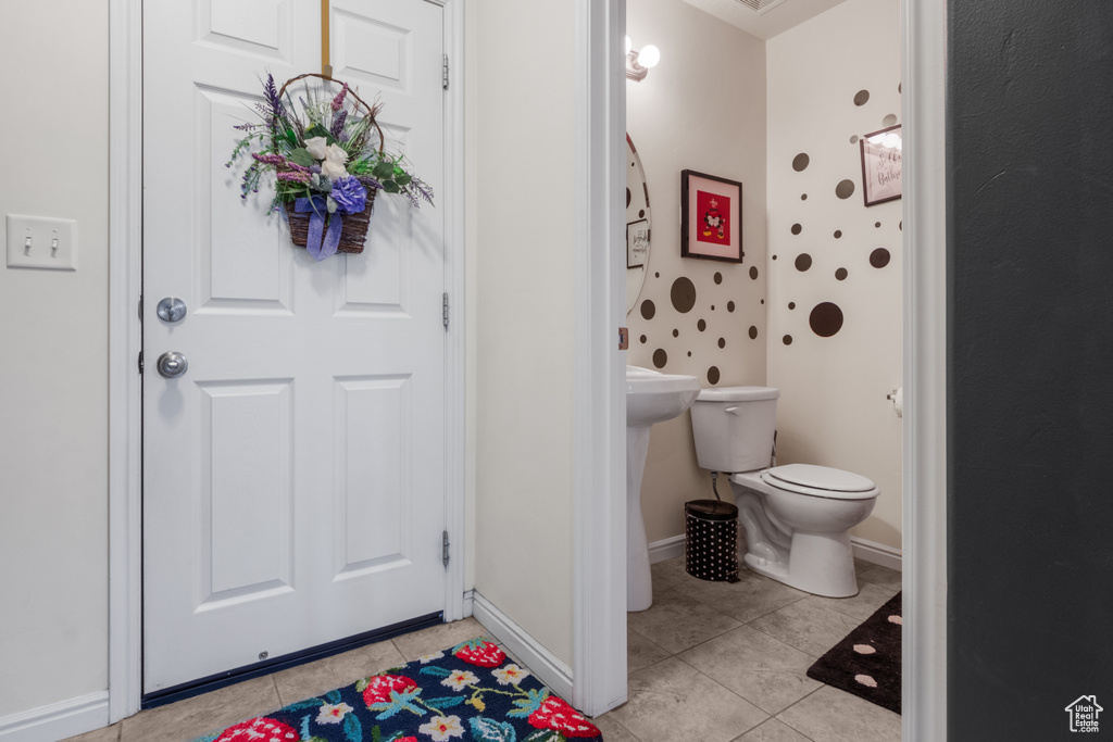 Bathroom with tile patterned floors, toilet, and baseboards