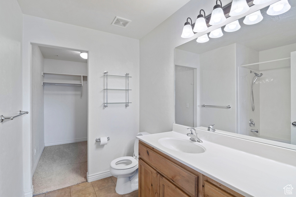 Bathroom with toilet, vanity, tile patterned floors, a walk in closet, and baseboards