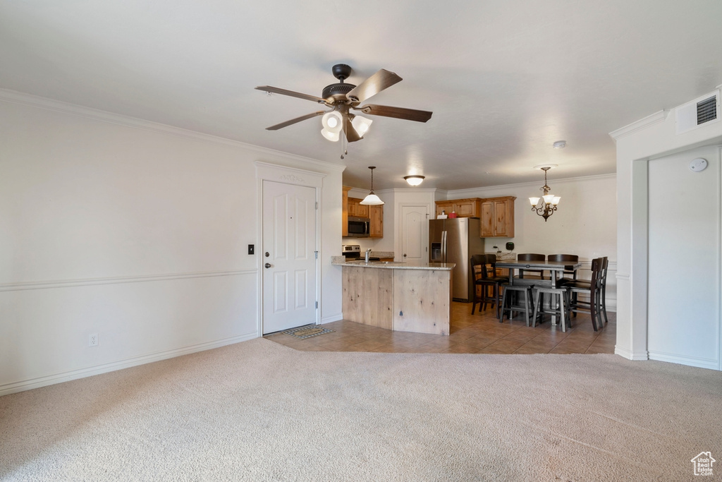 Living room with ornamental molding, a chandelier, a ceiling fan, light colored carpet, and baseboards