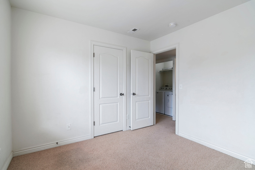 Unfurnished bedroom with washer and dryer, carpet, and baseboards