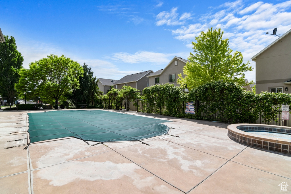 Community pool featuring a community hot tub, fence, a patio area, and a residential view