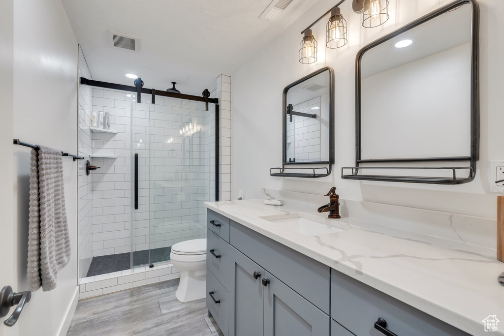 Bathroom featuring a shower stall, toilet, vanity, wood finished floors, and recessed lighting