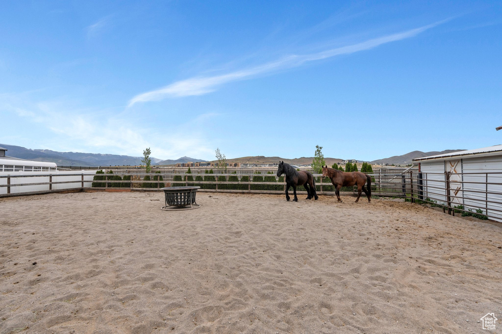 View of yard featuring a mountain view, an outdoor riding arena, an exterior structure, and a view of rural / pastoral area