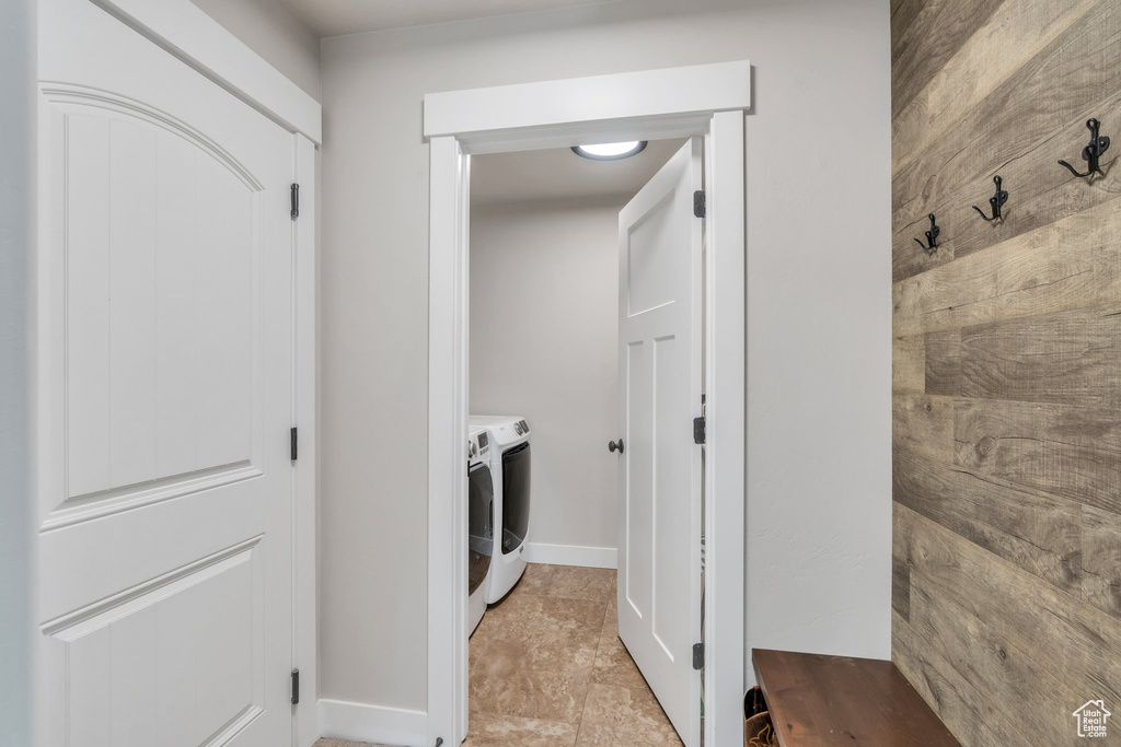Washroom featuring washer and clothes dryer, light tile patterned flooring, and baseboards