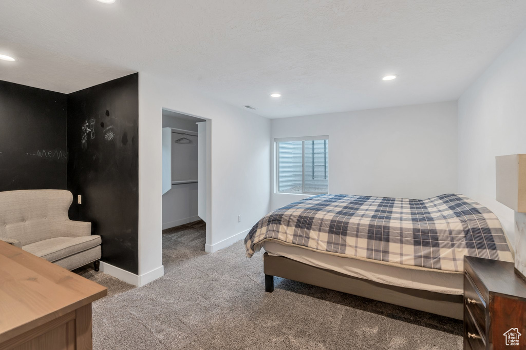 Carpeted bedroom featuring baseboards, recessed lighting, and a walk in closet