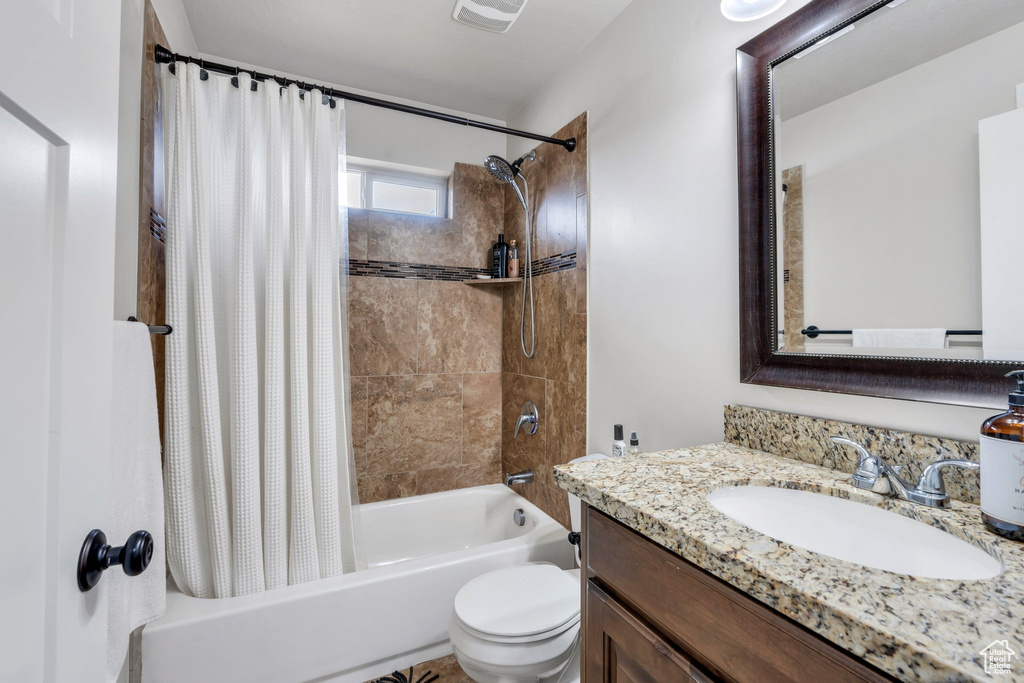 Bathroom featuring shower / bath combination with curtain, toilet, and vanity