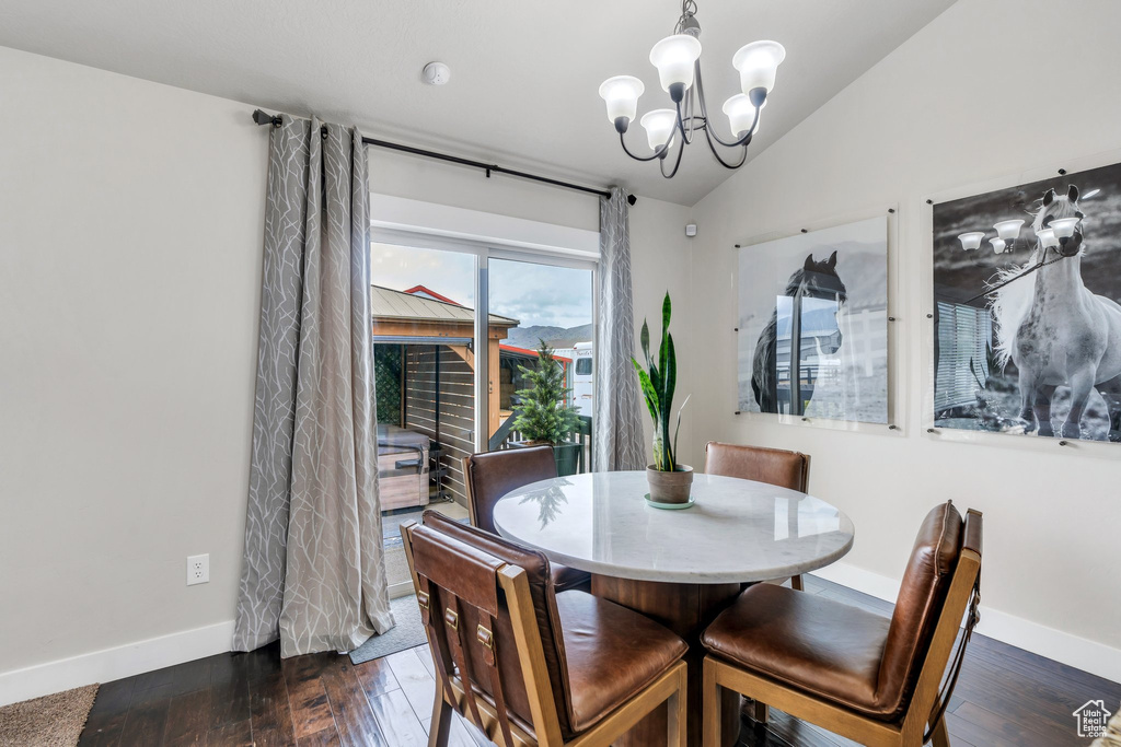 Dining space with vaulted ceiling, baseboards, a chandelier, and dark wood-type flooring