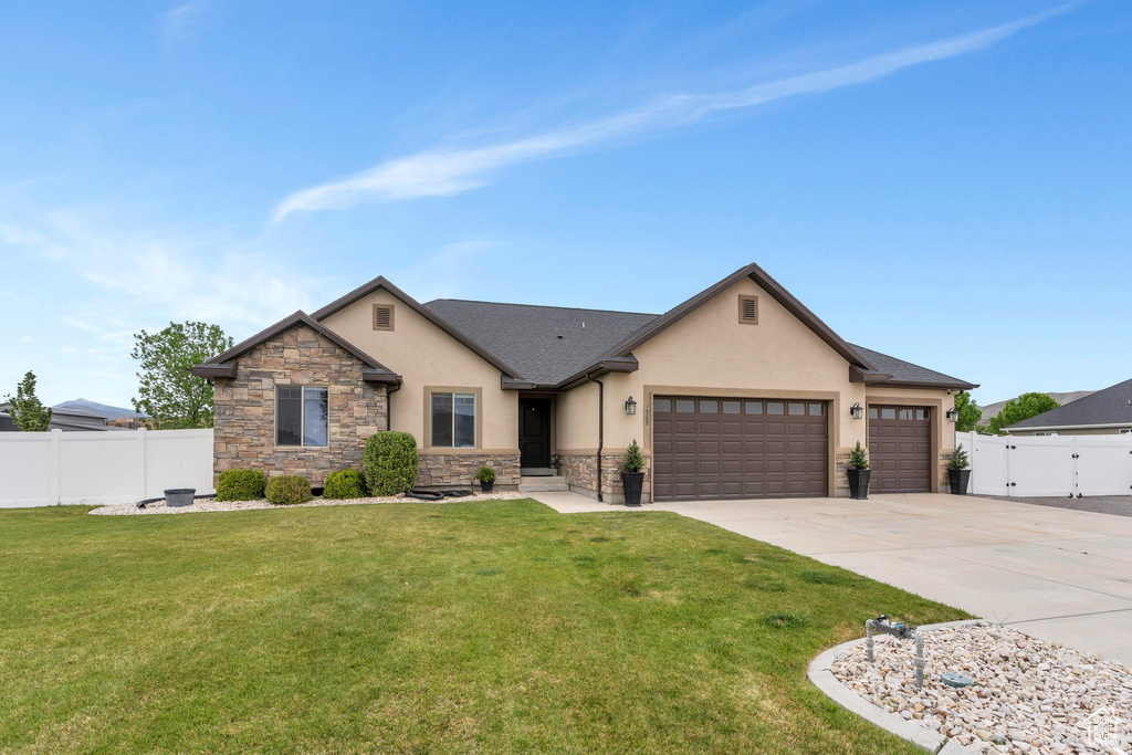 View of front facade featuring stucco siding, an attached garage, driveway, and stone siding