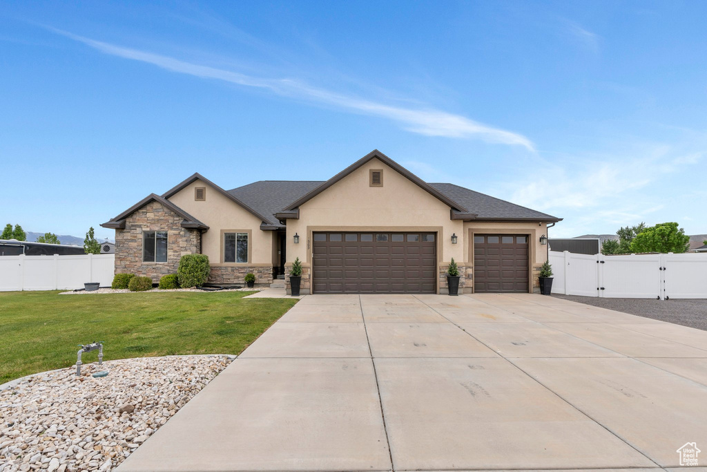 View of front of property featuring stucco siding, an attached garage, stone siding, concrete driveway, and a gate