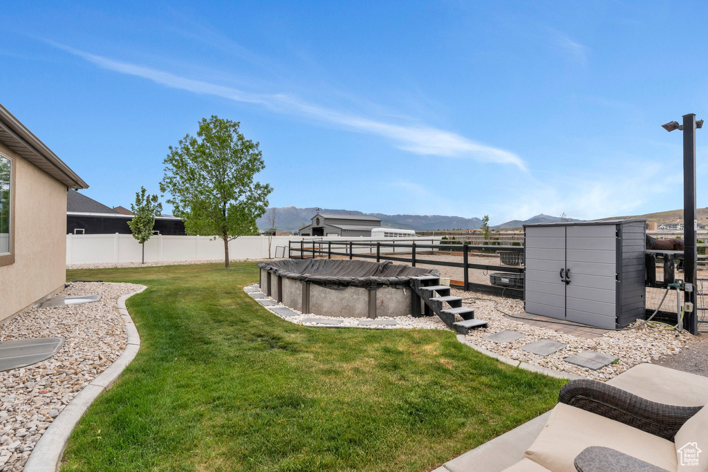 View of yard with a shed, a mountain view, and an outbuilding