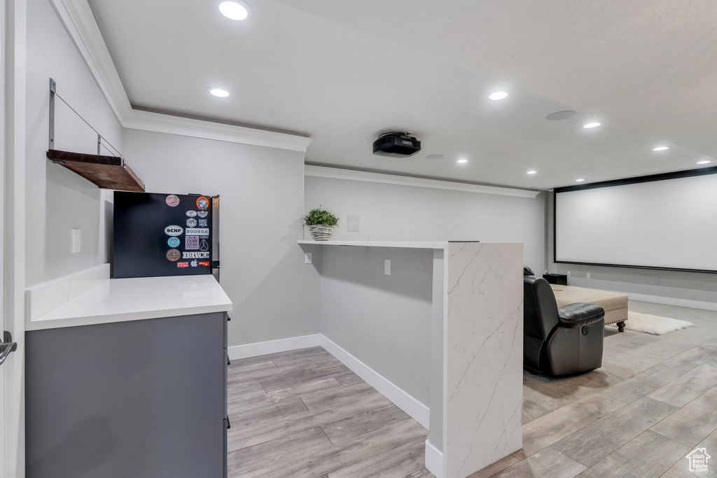 Home theater featuring ornamental molding, recessed lighting, light wood finished floors, and baseboards