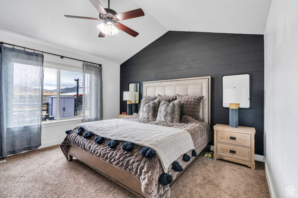 Bedroom featuring lofted ceiling, carpet flooring, ceiling fan, wood walls, and baseboards