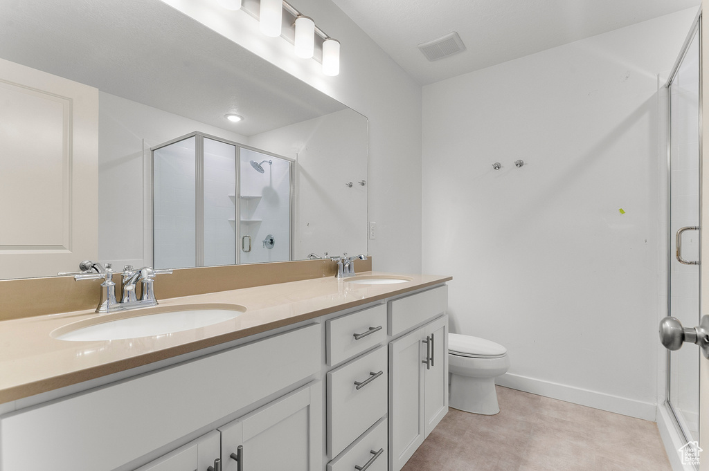 Bathroom with a stall shower, double vanity, toilet, and baseboards