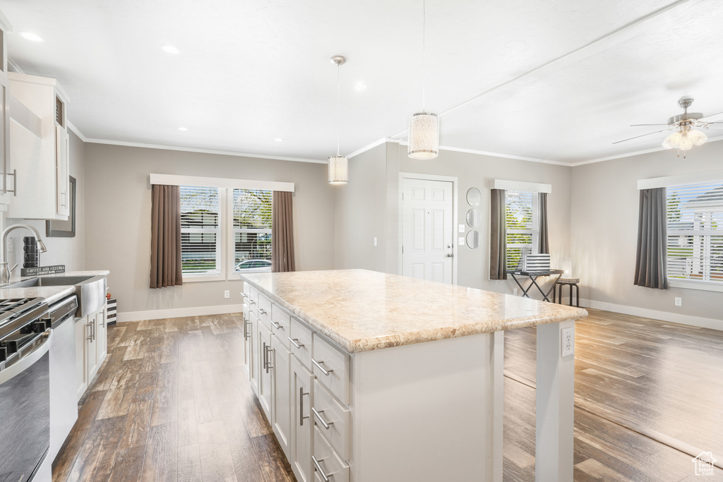 Kitchen featuring baseboards, dark wood-style floors, a kitchen island, white cabinetry, and ornamental molding