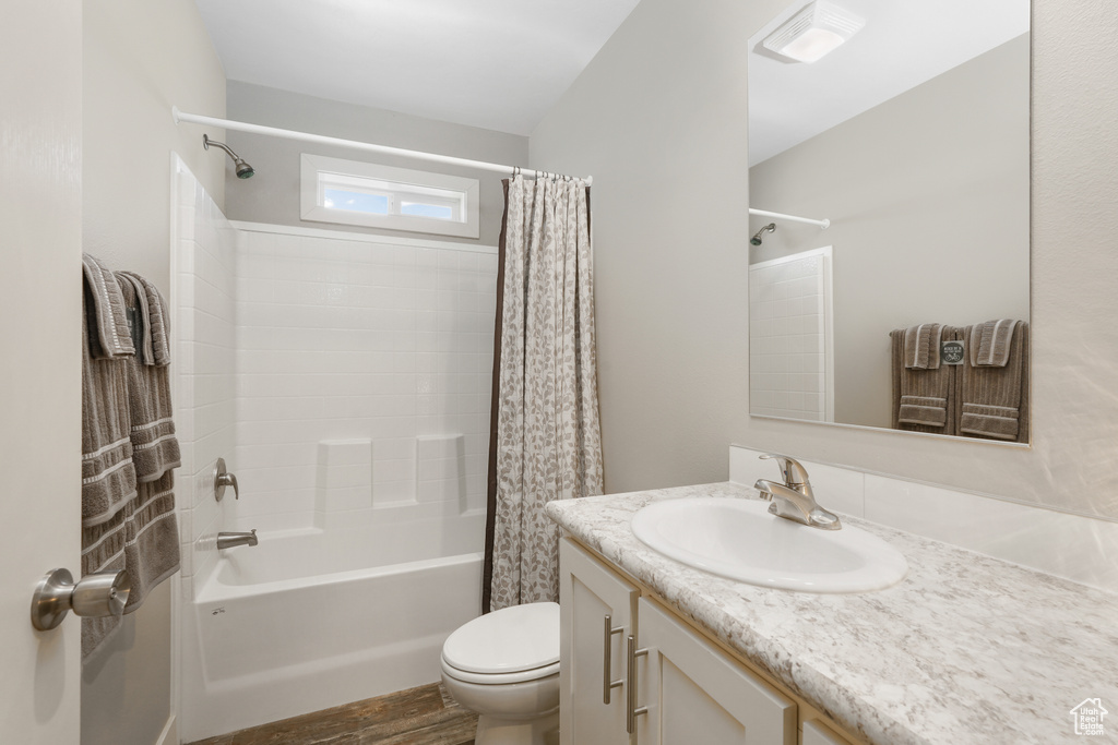 Bathroom featuring shower / bath combo with shower curtain, toilet, vanity, and wood finished floors