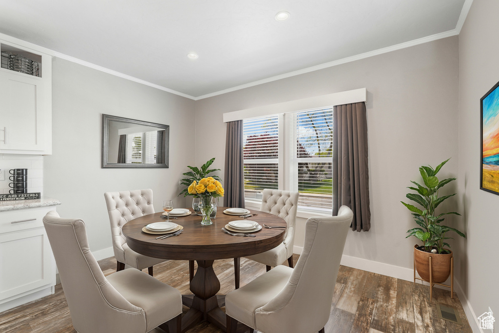 Dining space with baseboards, crown molding, dark wood-style floors, and recessed lighting