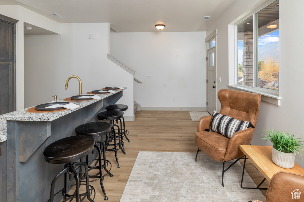 Indoor wet bar featuring light wood-style flooring, stairs, and baseboards