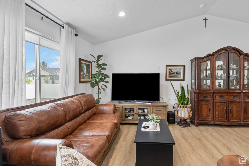 Living room with lofted ceiling, light wood-style floors, and recessed lighting