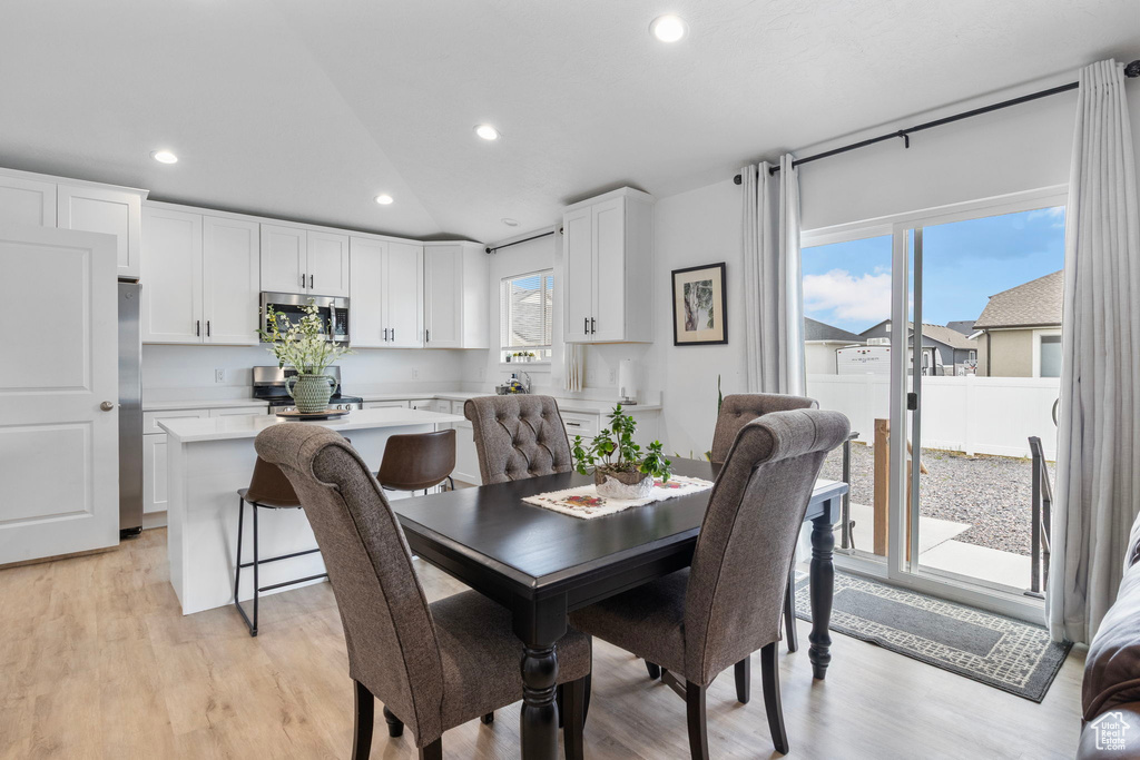 Dining space with light wood-style floors, lofted ceiling, and recessed lighting