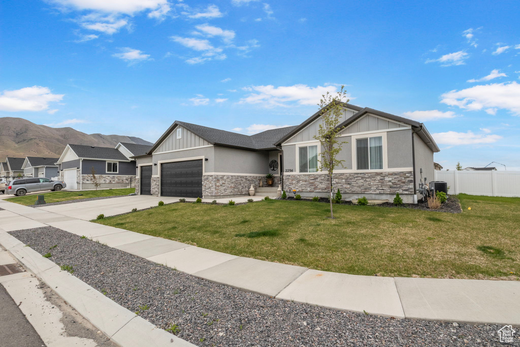 View of front of home featuring stone siding, an attached garage, driveway, and board and batten siding