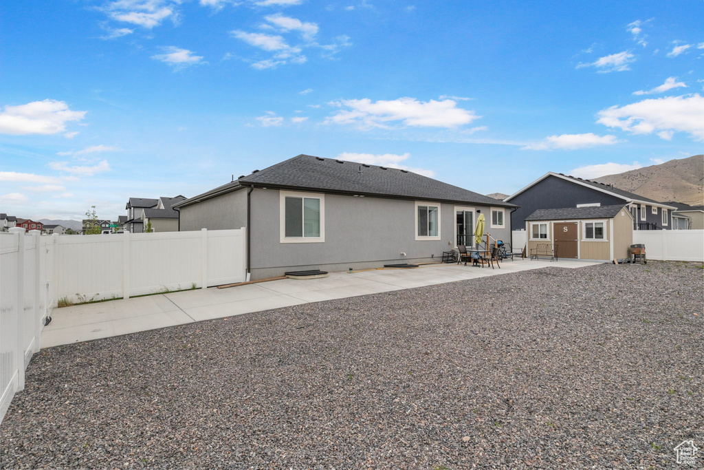 Rear view of house with a patio area, a fenced backyard, roof with shingles, and stucco siding