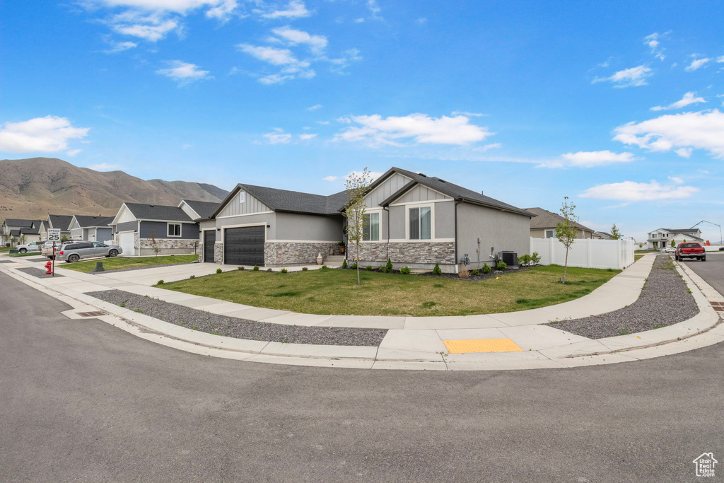 View of front of house with stone siding, a residential view, a garage, concrete driveway, and board and batten siding