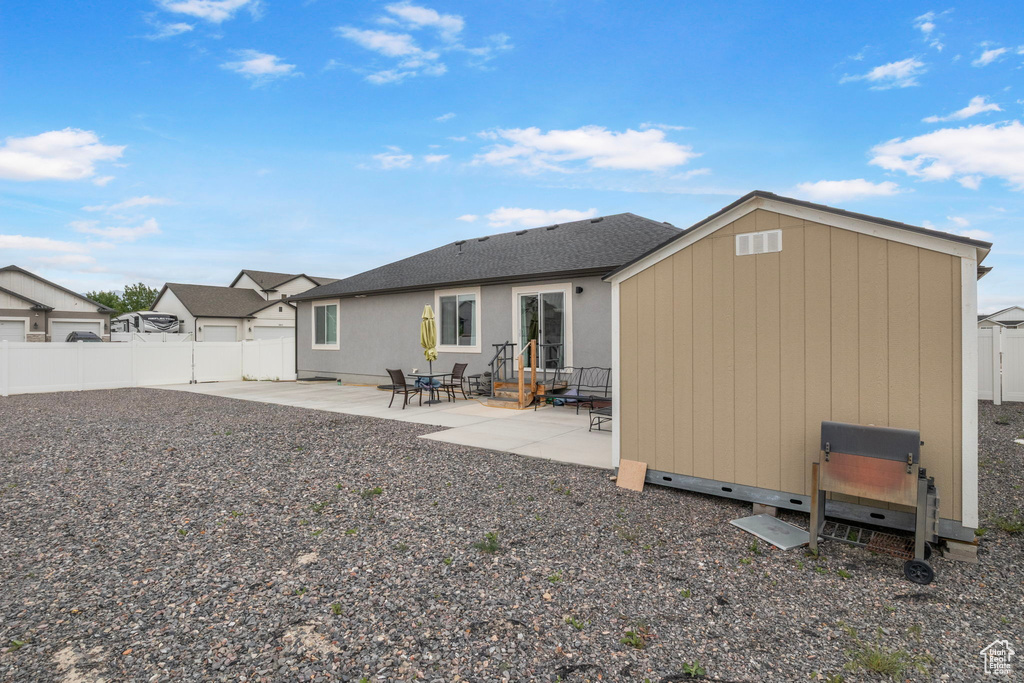Back of house featuring a patio, a fenced backyard, an outbuilding, and a shed