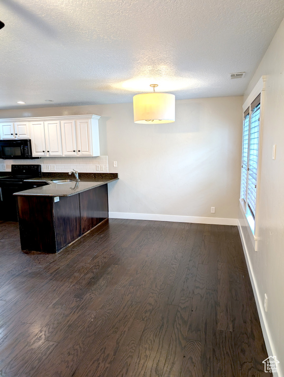 Kitchen with black appliances, dark wood-style flooring, a sink, a peninsula, and dark countertops