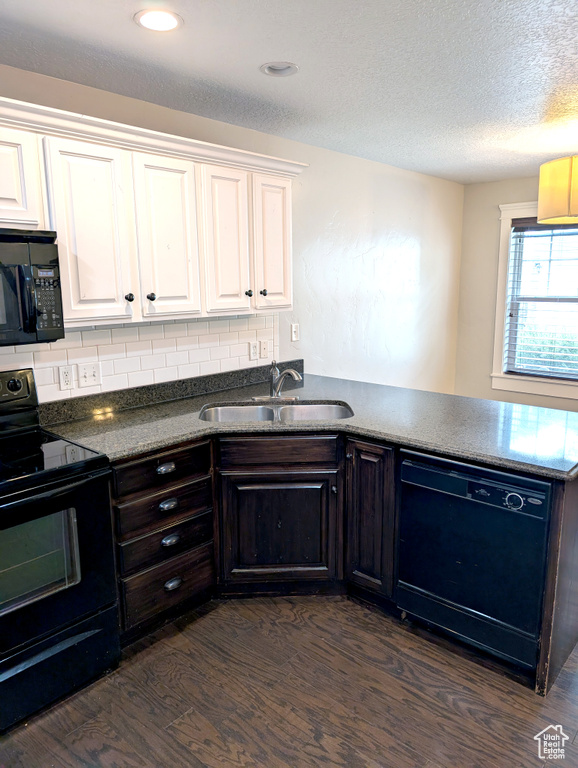 Kitchen featuring black appliances, a sink, dark wood-type flooring, a peninsula, and white cabinetry