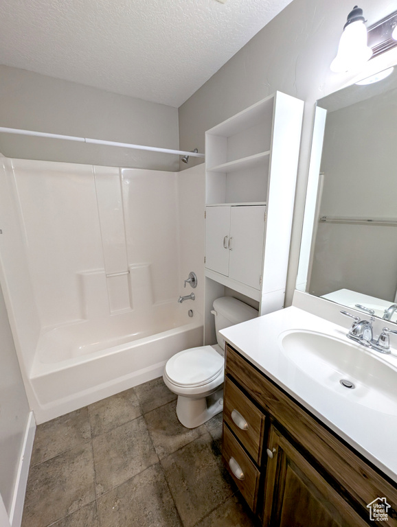 Bathroom featuring toilet, vanity, shower / tub combination, a textured ceiling, and baseboards