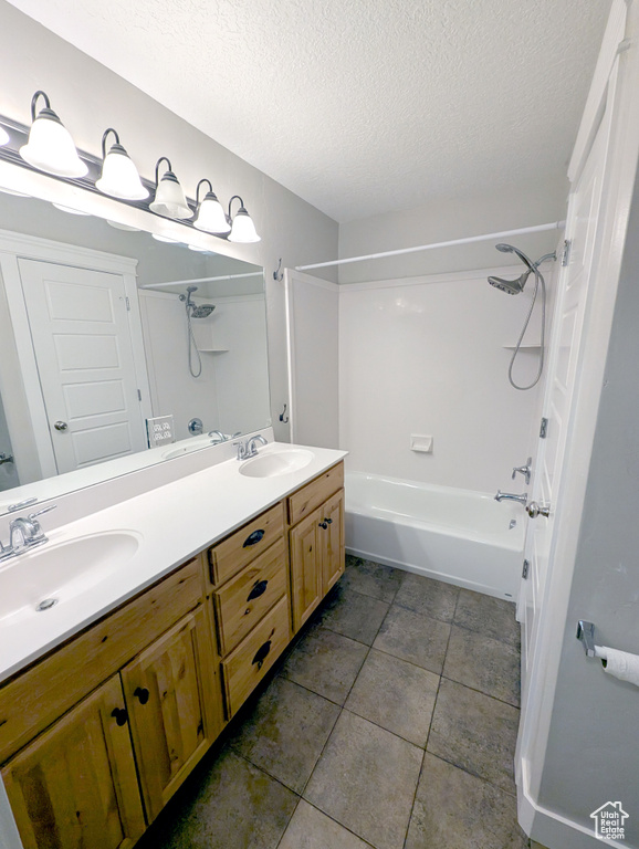 Bathroom featuring a textured ceiling, double vanity, bathing tub / shower combination, and tile patterned floors