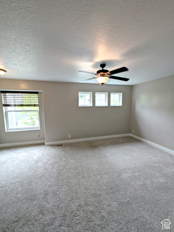 Unfurnished room featuring a textured ceiling, carpet flooring, ceiling fan, and baseboards