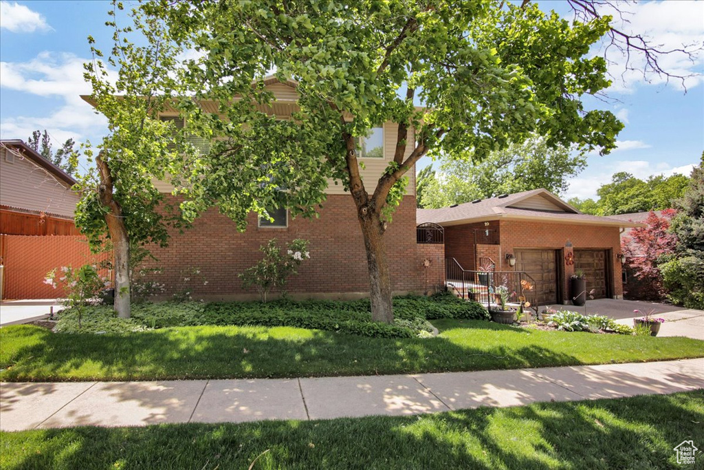 View of front of home featuring brick siding, a front yard, a garage, and concrete driveway