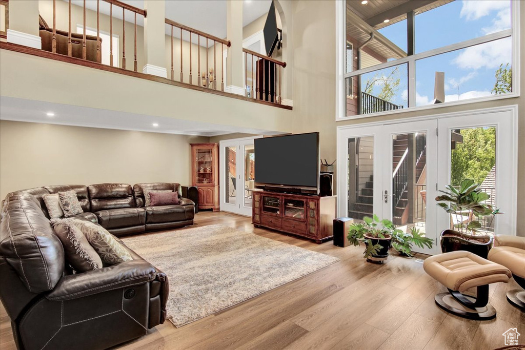 Living area featuring a towering ceiling, wood finished floors, recessed lighting, and french doors