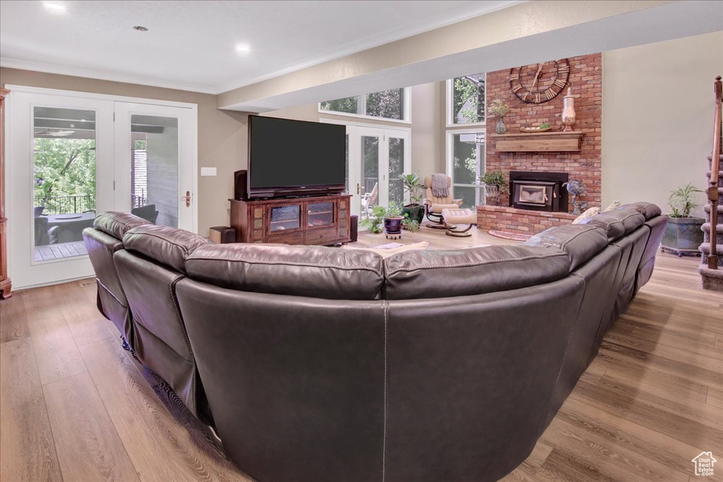 Living area featuring french doors, ornamental molding, wood finished floors, a brick fireplace, and recessed lighting