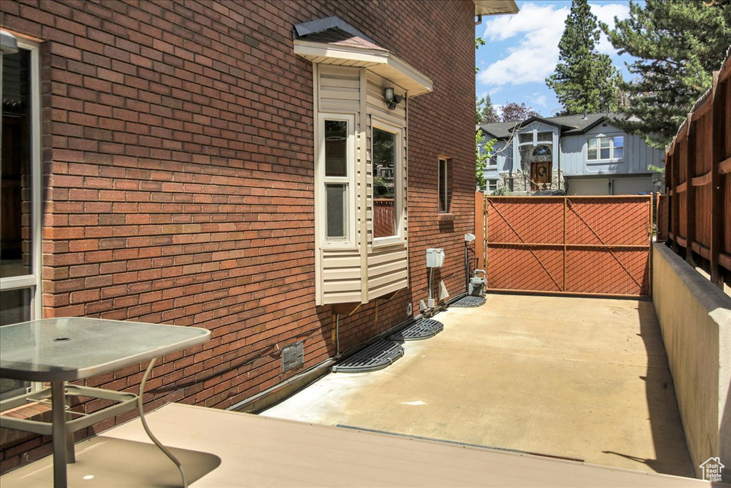 View of property exterior with brick siding, a patio, and fence