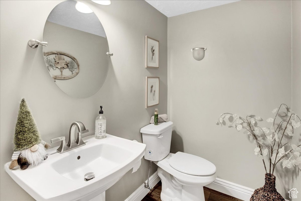 Bathroom featuring toilet, wood finished floors, a sink, and baseboards