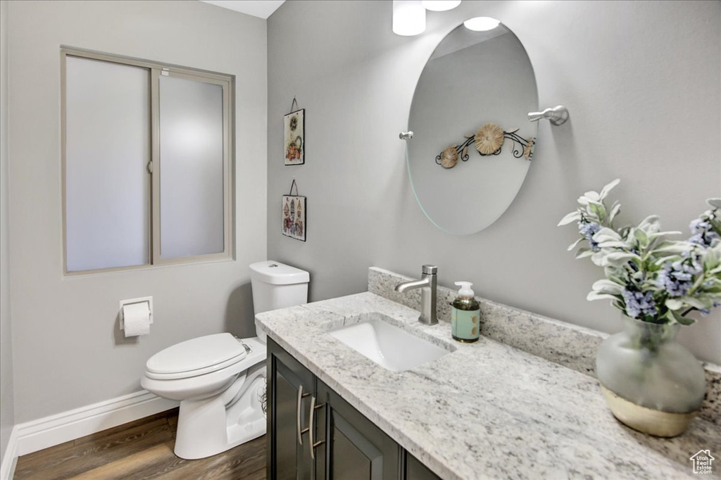 Bathroom with toilet, wood finished floors, vanity, and baseboards