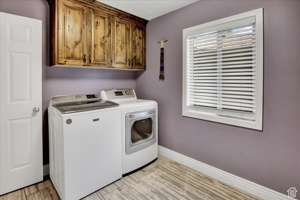 Laundry area featuring washing machine and dryer, cabinet space, and baseboards
