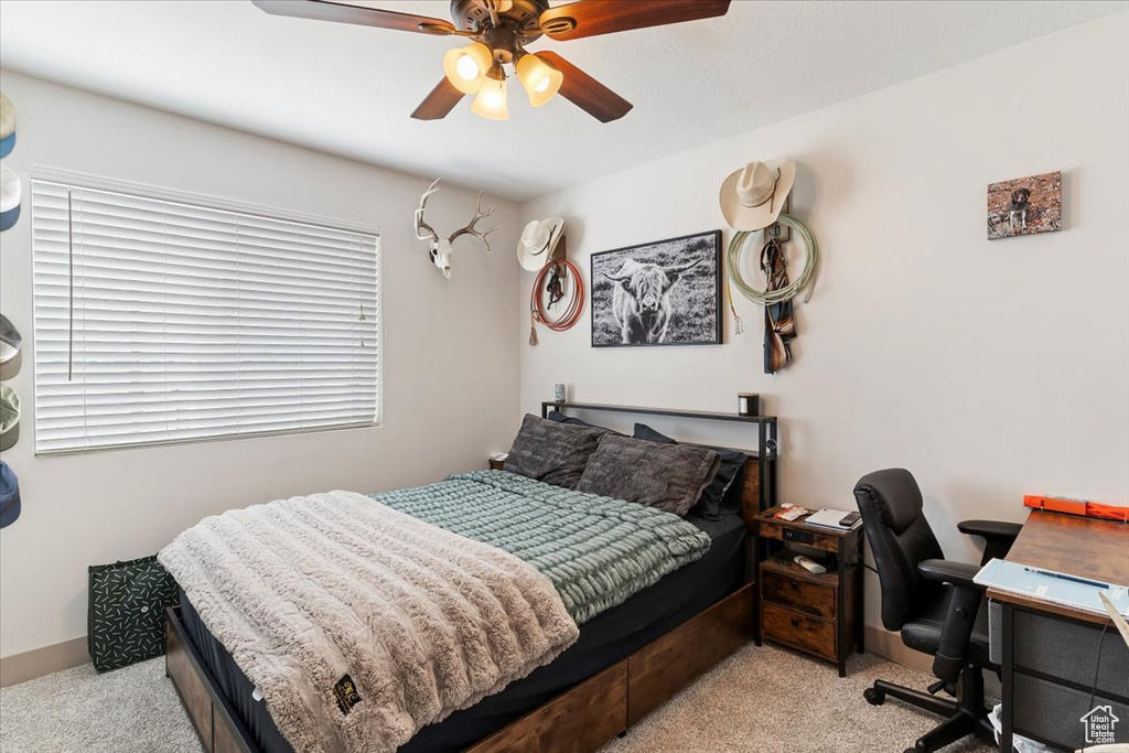 Carpeted bedroom featuring a desk and ceiling fan