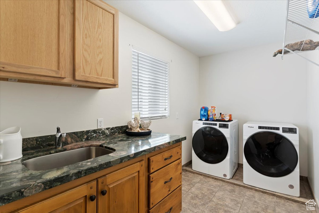 Clothes washing area with cabinet space, washer and clothes dryer, and light tile patterned floors