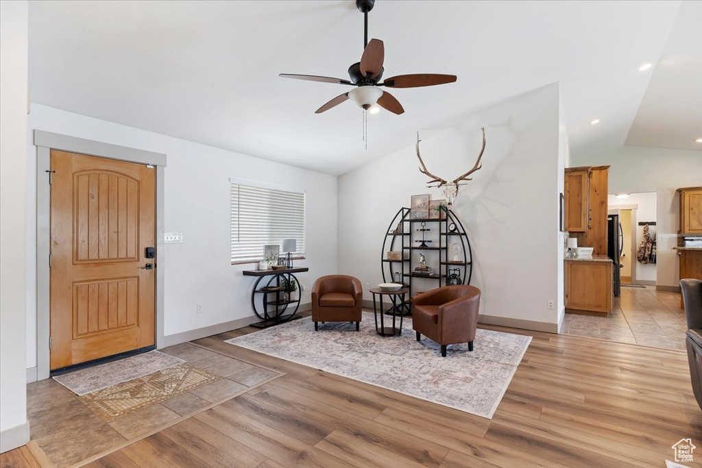 Sitting room with vaulted ceiling, a ceiling fan, light wood finished floors, and baseboards