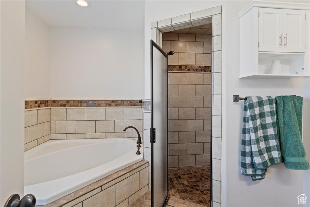 Full bathroom with a stall shower, a bath, and recessed lighting