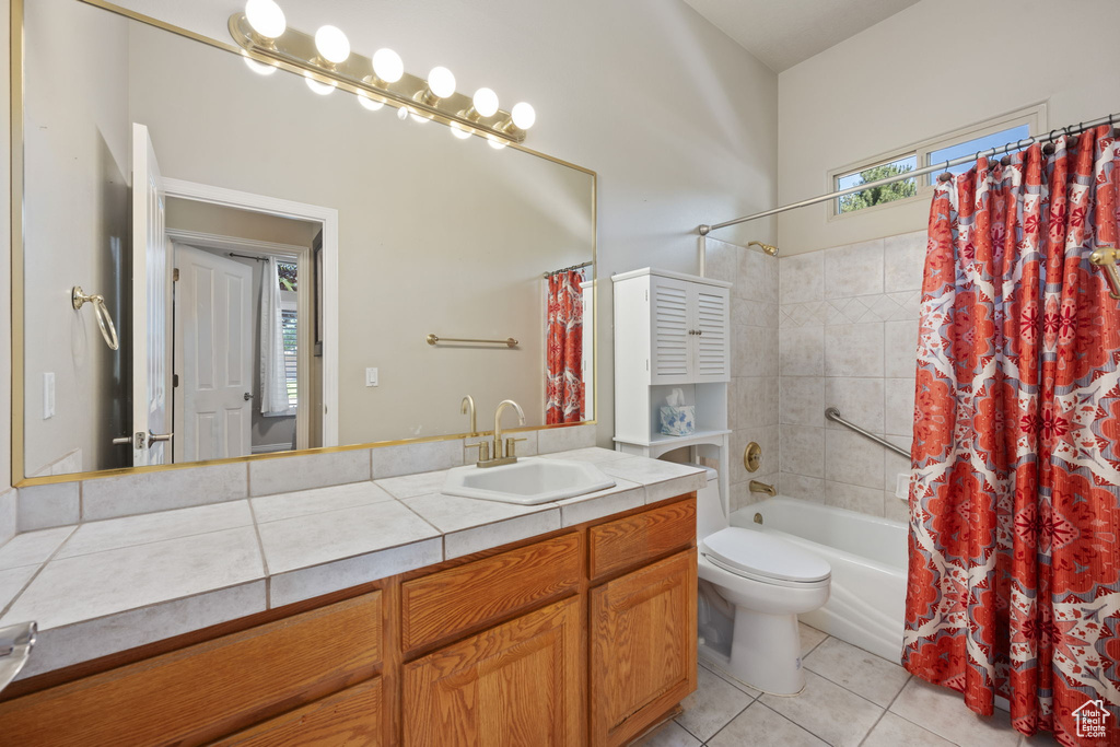 Full bath with tile patterned flooring, shower / bath combination with curtain, toilet, and vanity