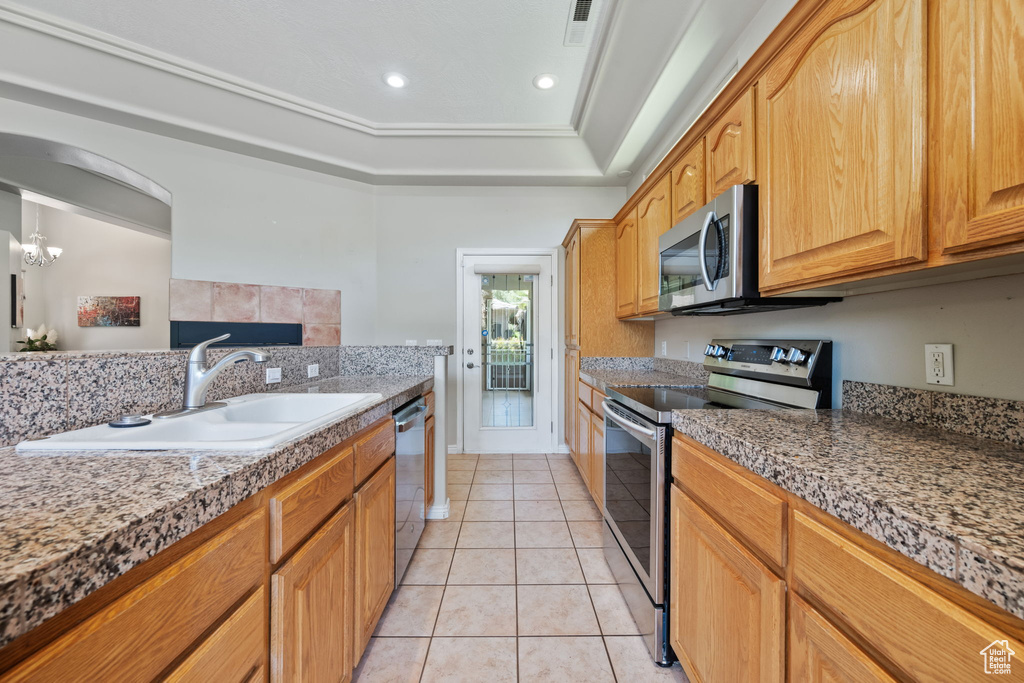 Kitchen featuring stainless steel appliances, a sink, light tile patterned floors, recessed lighting, and a tray ceiling