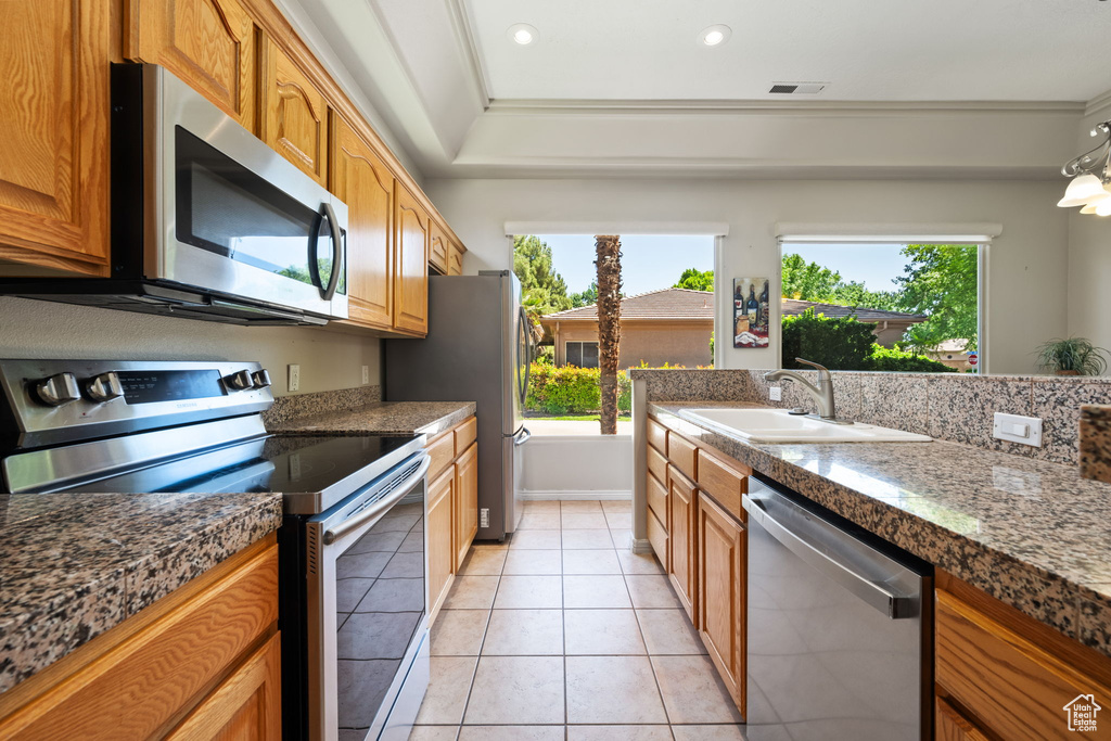 Kitchen with appliances with stainless steel finishes, a sink, healthy amount of natural light, brown cabinets, and recessed lighting