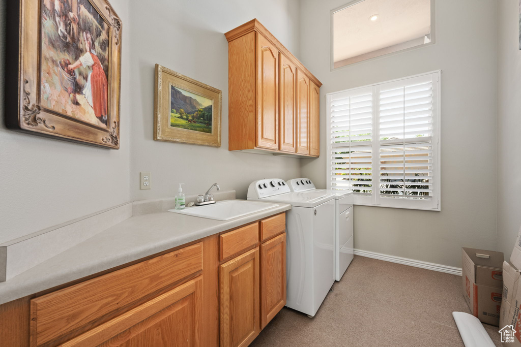 Laundry room with cabinet space, washer and dryer, light carpet, and baseboards