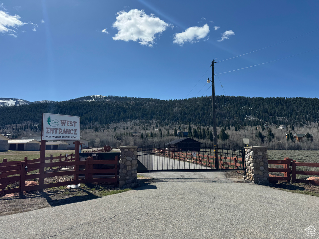 View of asphalt road with a mountain view, a wooded view, and a gate