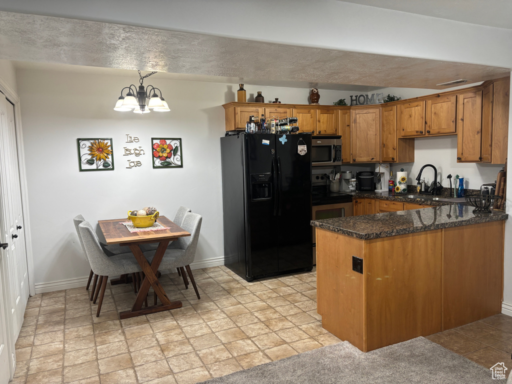 Kitchen featuring appliances with stainless steel finishes, brown cabinets, a peninsula, and baseboards